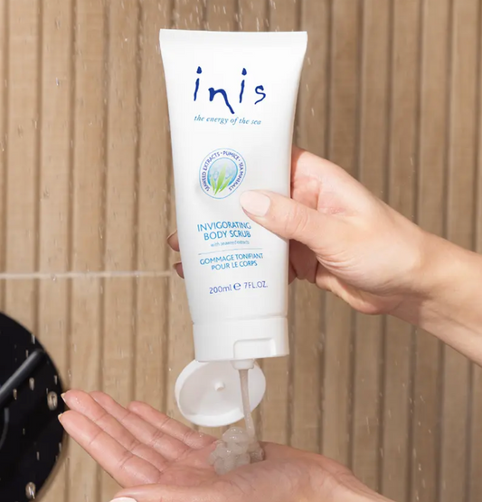 Inis Invigorating Body Scrub with seaweed extracts being dispensed onto hand in shower