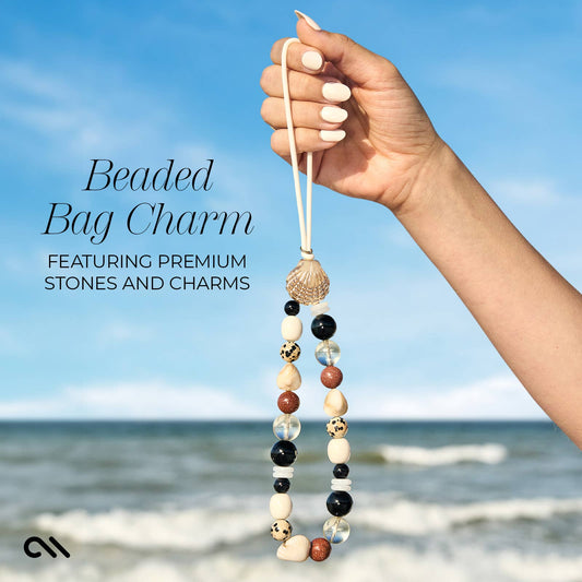 Neutral beaded bag charm with mixed stones and gold shell accent held at the beach