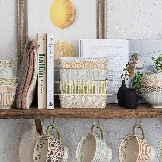 Four hand-stamped stoneware baking dishes in orange geometric, blue botanical, green stripe and brown medallion patterns