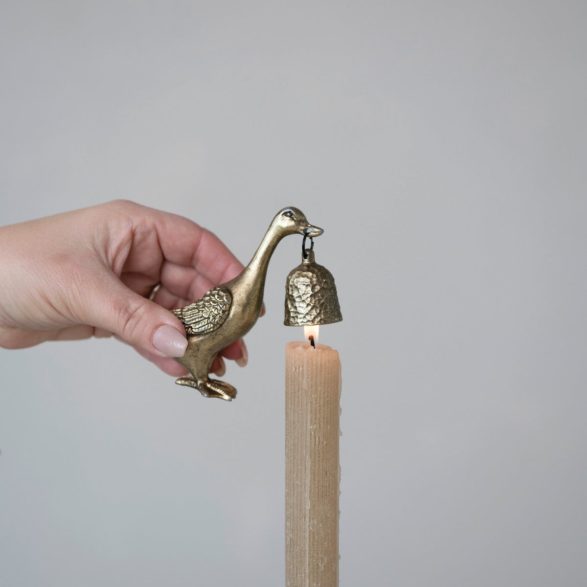 Antique gold duck candle snuffer extinguishing a taper candle