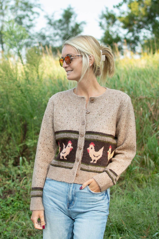 Women's Heritage Chicken Cardigan in oatmeal knit with brown chicken pattern, olive green accents and button-front closure, styled with blue jeans.