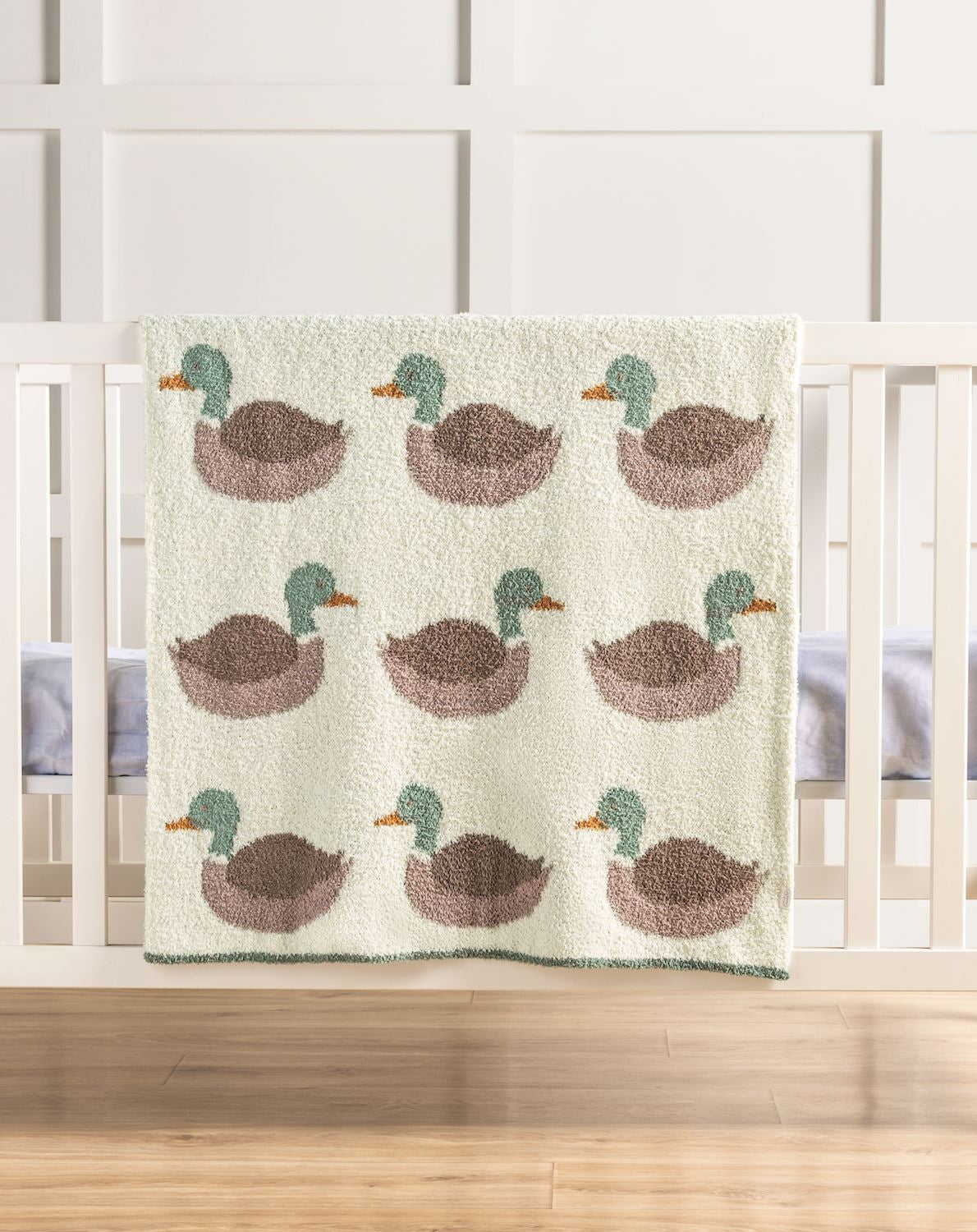 Mallard duck chenille baby blanket with sage green and brown ducks displayed on white crib in hunting nursery