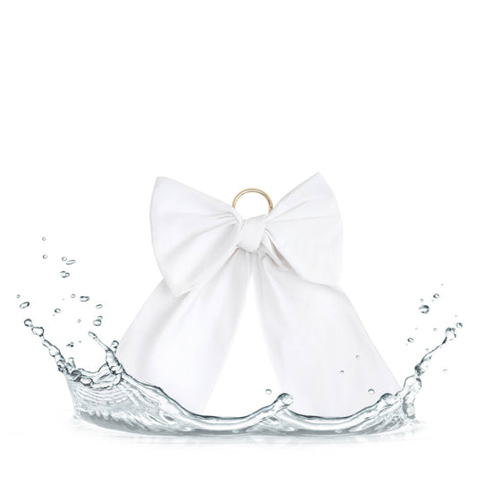 Oversized white bow bag charm on beach tote with waterproof fabric and gold hardware