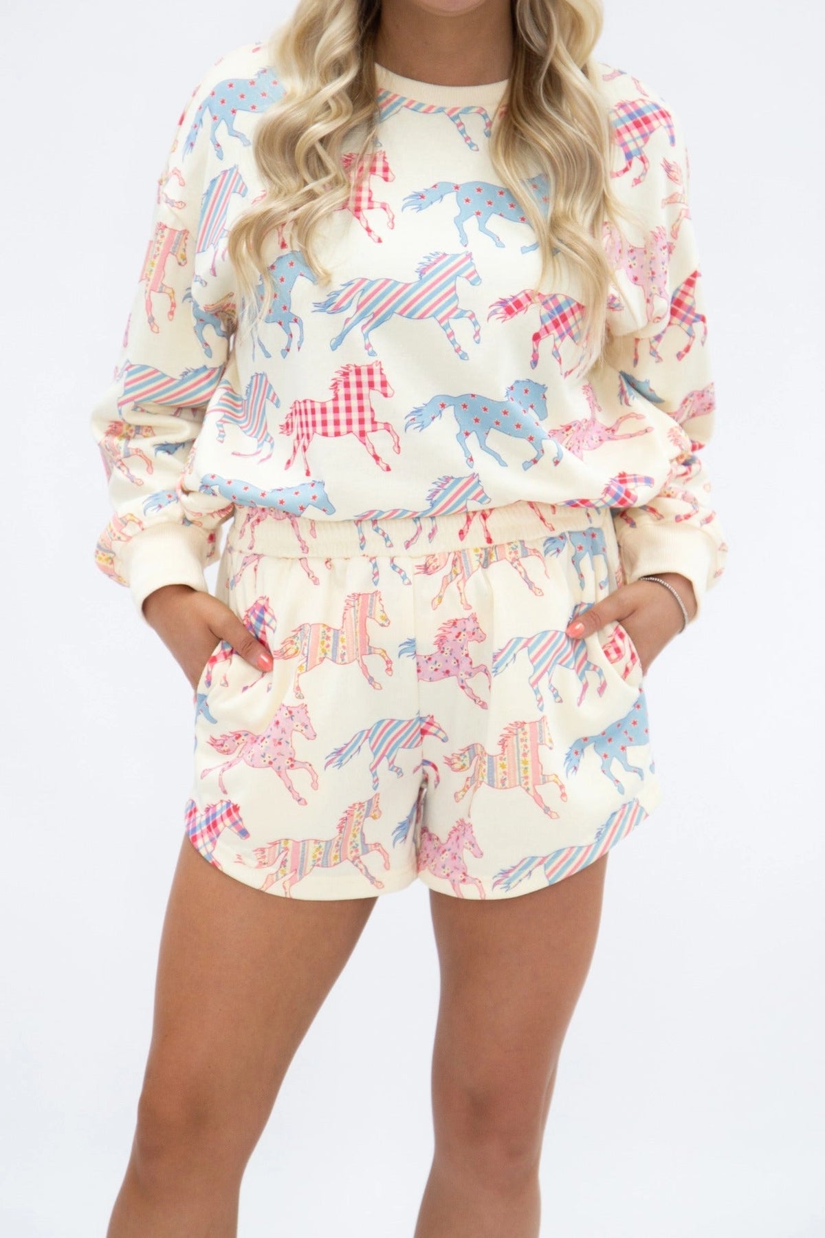 Women's Wild at Heart horse print two-piece lounge set featuring cream long-sleeve sweatshirt and matching shorts with colorful pink and blue patterned horses