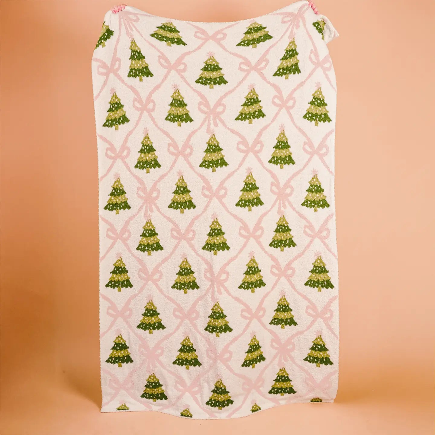 Pink bow and green Christmas tree cozy throw blanket on cream background
