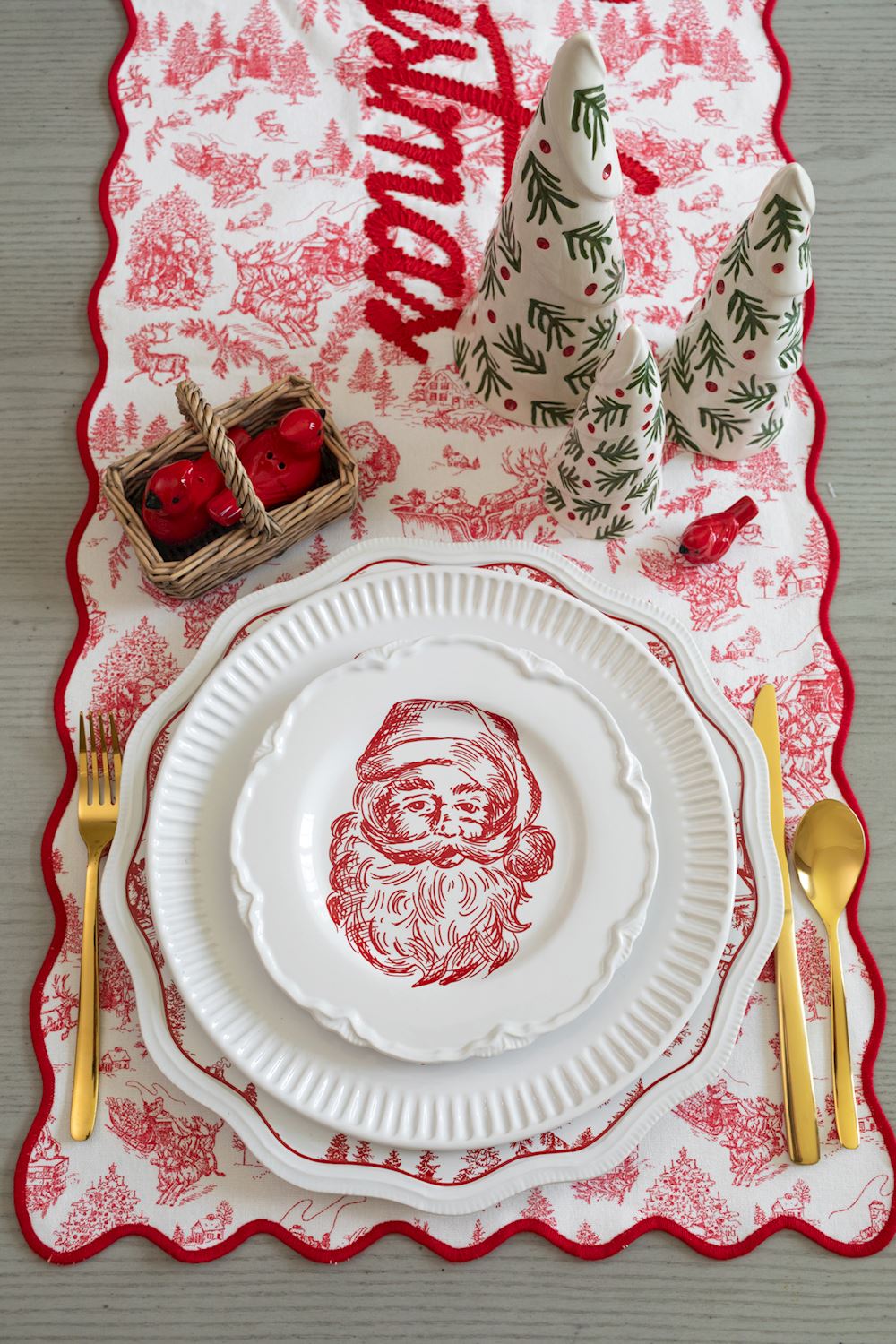 Mud Pie red cardinal mini keepsake displayed in a Christmas table setting with Santa plates, festive greenery, and holiday decorations.