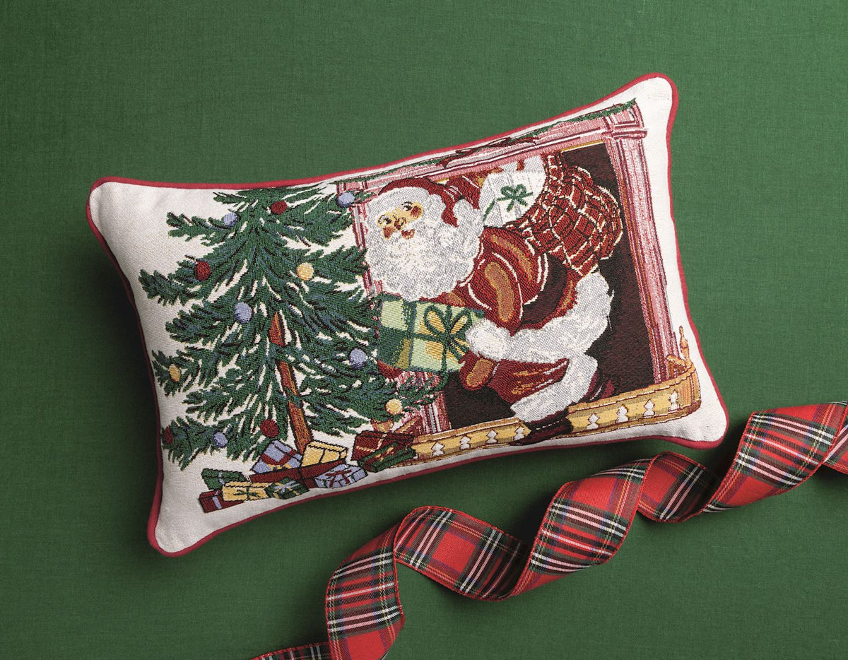 Mud Pie Santa Christmas tapestry throw pillow styled on a green background with festive red plaid ribbon