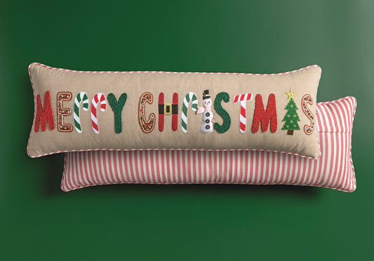 Mud Pie Merry Christmas 35-inch lumbar pillow with colorful beaded and felt holiday lettering, styled with red and white striped backing against a green background.