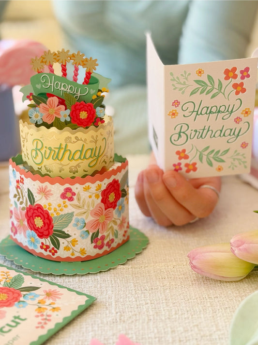FreshCut Paper Mini Blooming Birthday Cake 3D pop-up greeting card with colorful floral two-tier cake, birthday candles, and matching Happy Birthday notecard