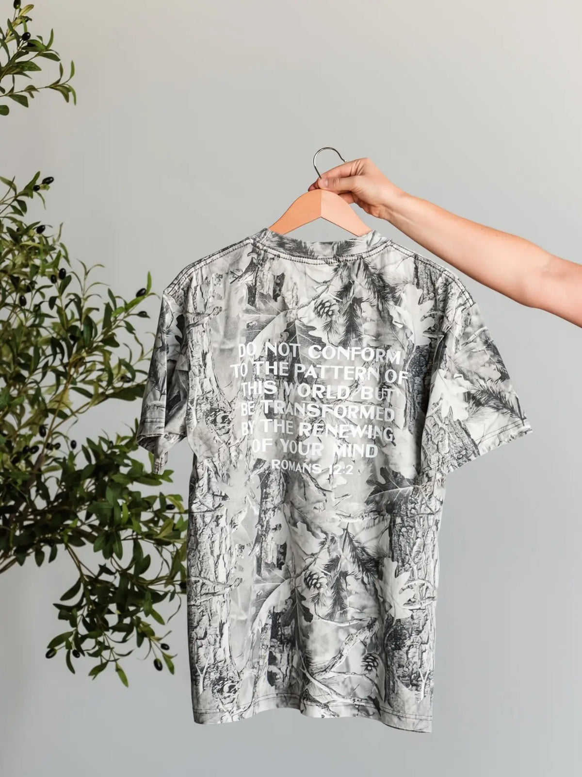 Word Over World Christian camo graphic tee with Romans 12:2 scripture on back