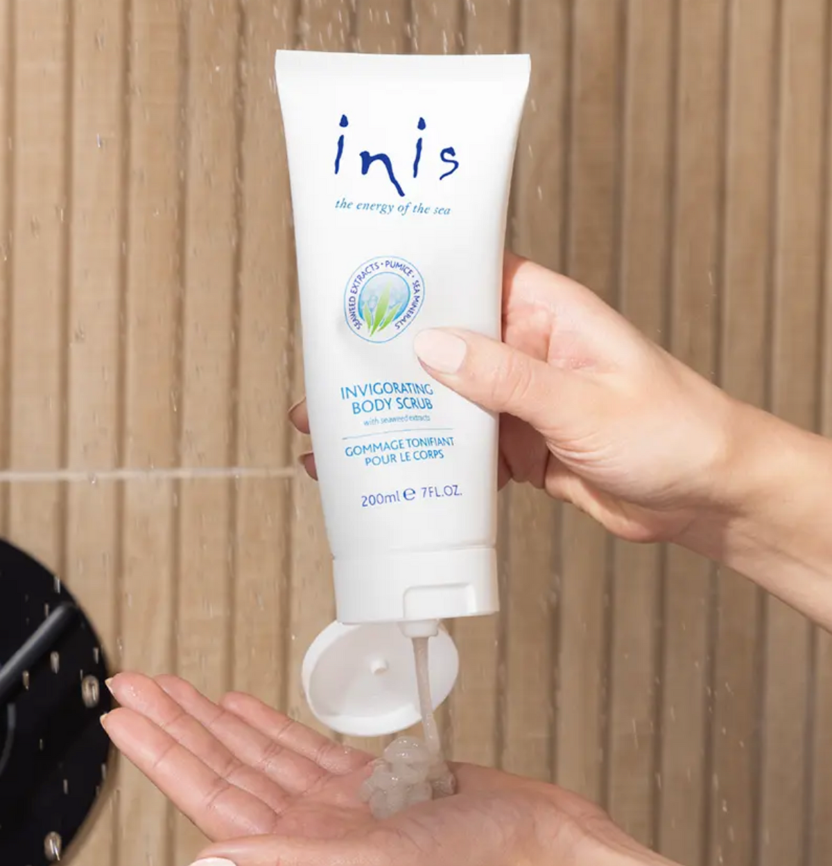 Inis Invigorating Body Scrub with seaweed extracts being dispensed onto hand in shower
