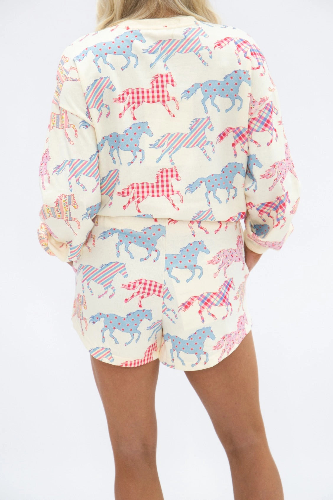 Women's Wild at Heart horse print two-piece lounge set featuring cream long-sleeve sweatshirt and matching shorts with colorful pink and blue patterned horses