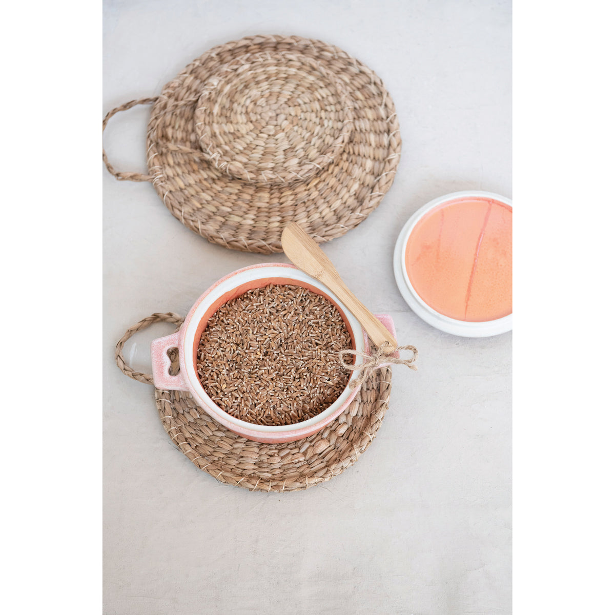Pink stoneware brie baker with bamboo spreader styled with baked brie and serving plate