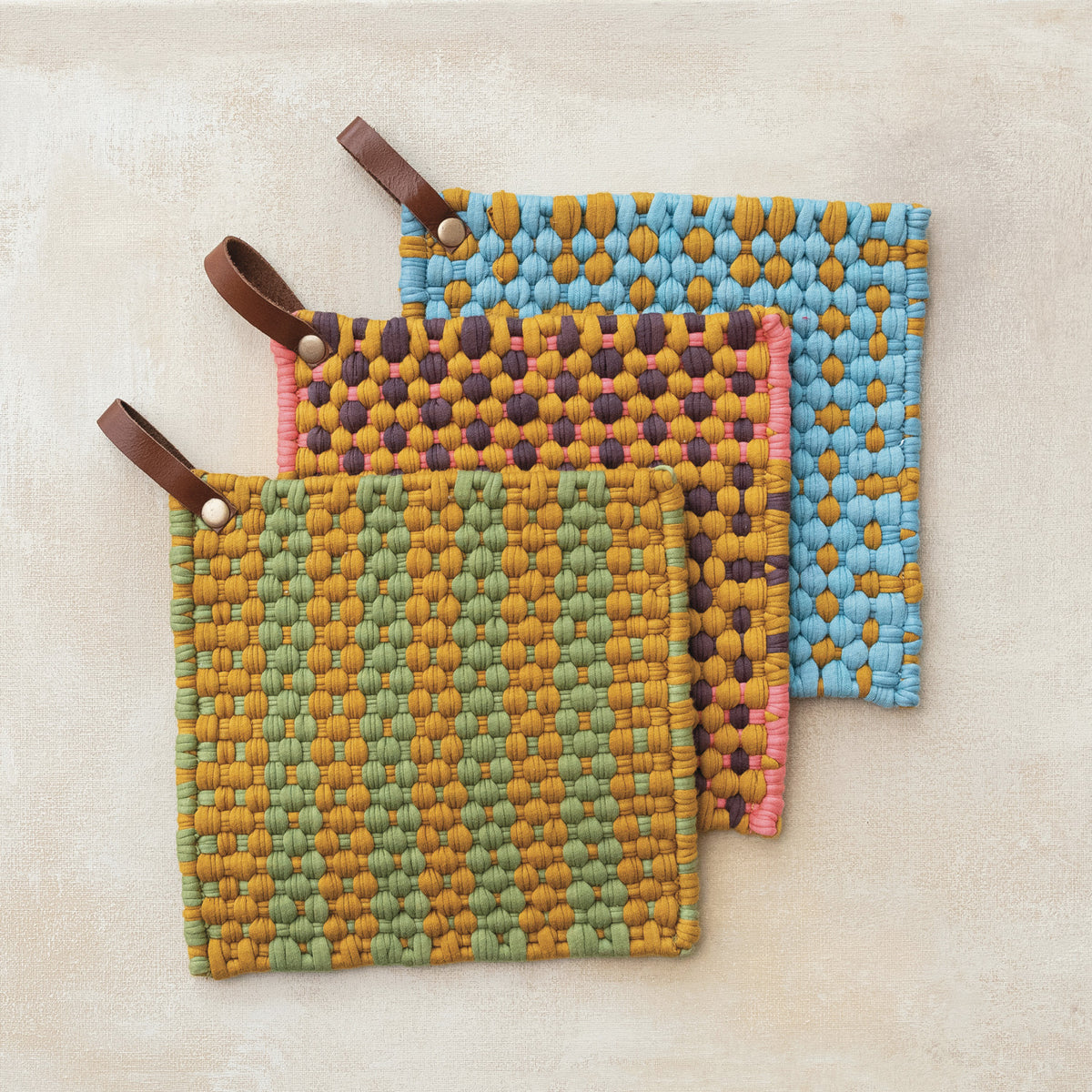 Colorful woven cotton pot holders with leather hanging loops in sage, pink and blue