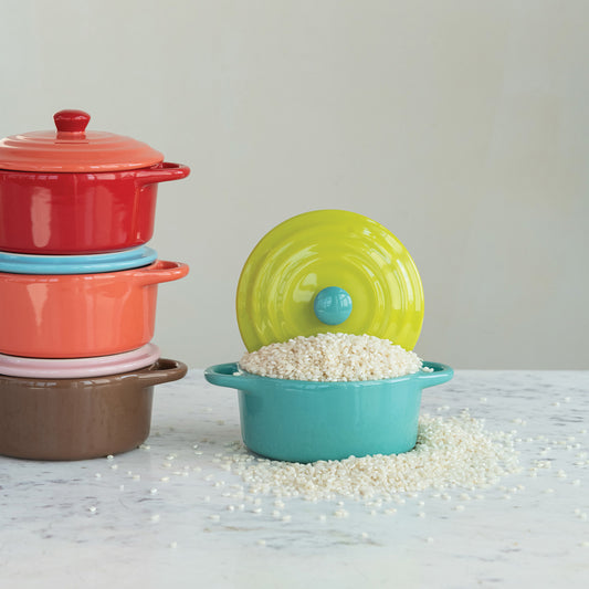 Colorful mini stoneware bakers with lids stacked on kitchen counter with turquoise baker displayed open
