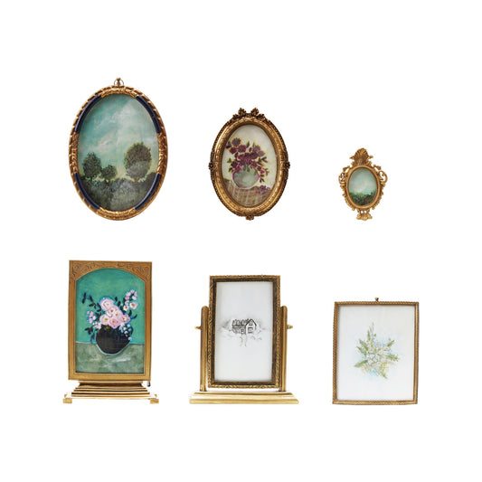 Six vintage-inspired gold pewter and glass picture frames in ornate oval and rectangular styles with artwork