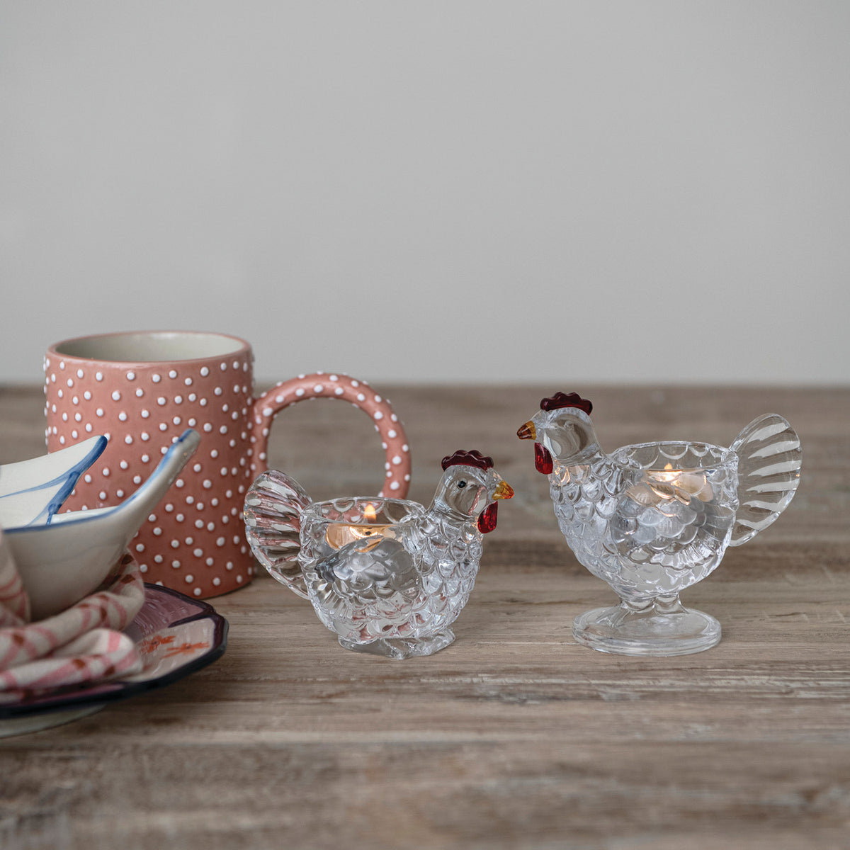Clear glass hen votive candle holders in two sizes styled on farmhouse table