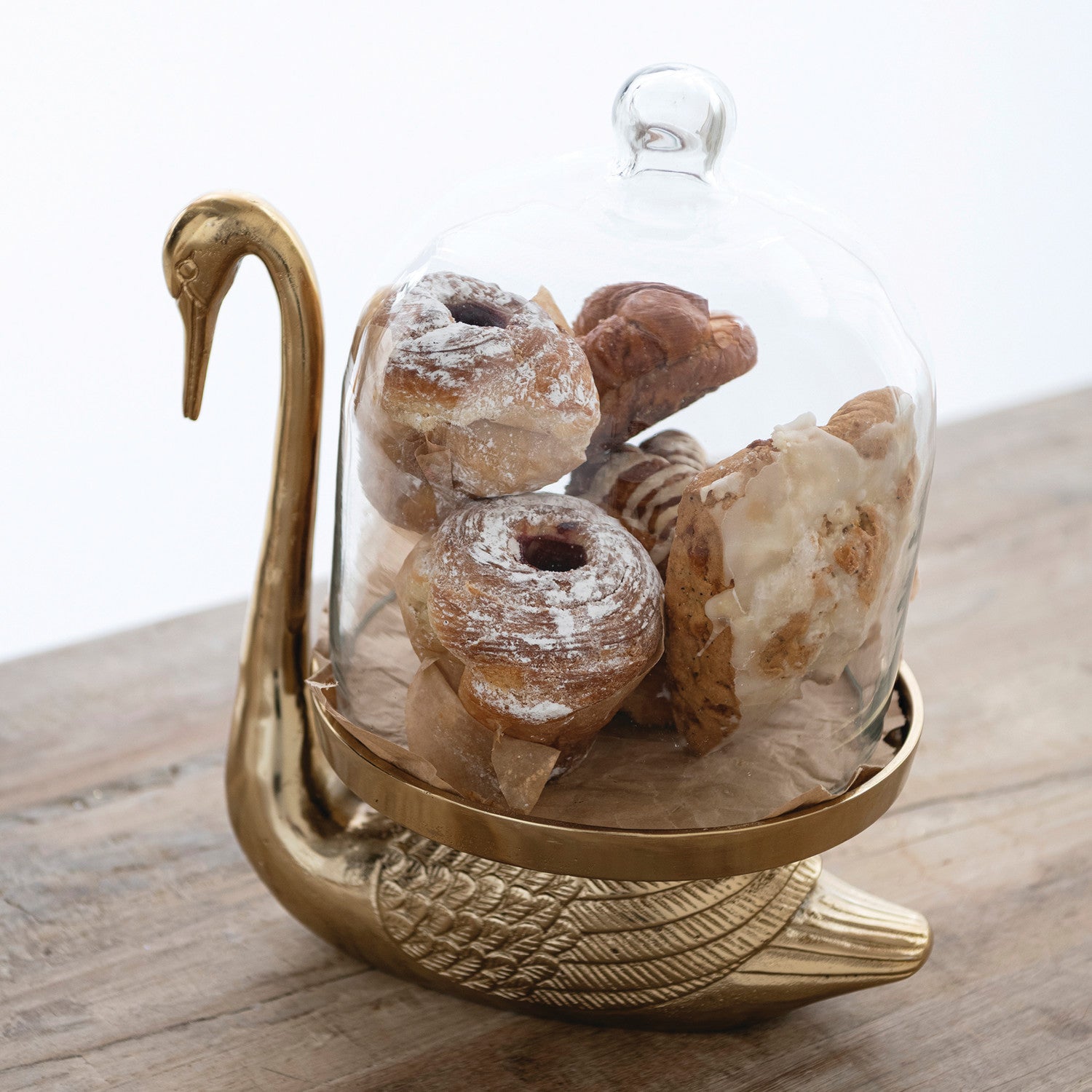 Antique gold swan serving stand with clear glass cloche dome for displaying pastries and treats
