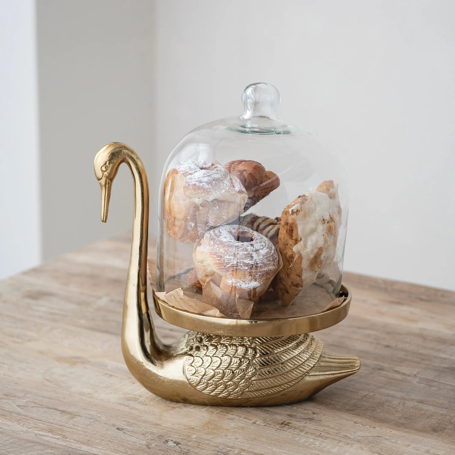 Antique gold swan serving stand with clear glass cloche dome for displaying pastries and treats
