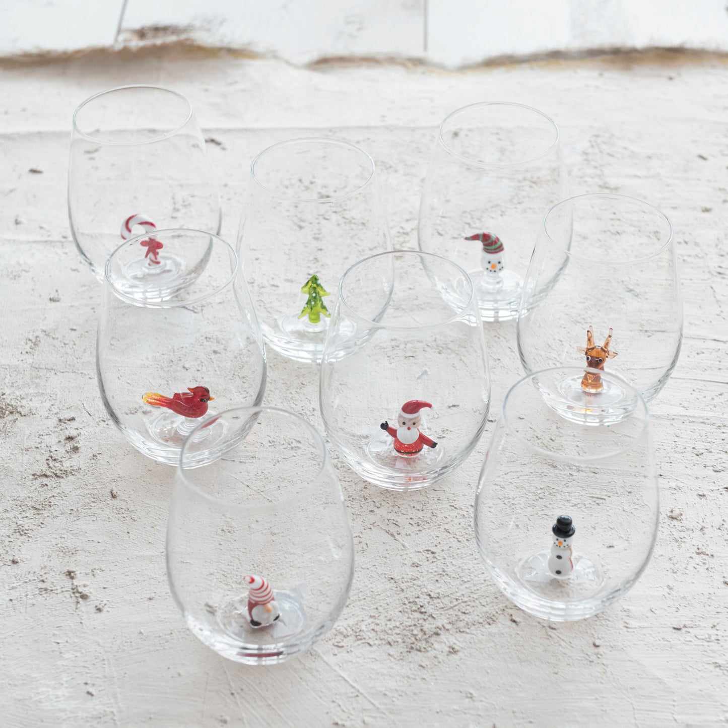 Assorted Christmas stemless wine glasses with miniature Santa snowman reindeer cardinal tree and candy cane figures