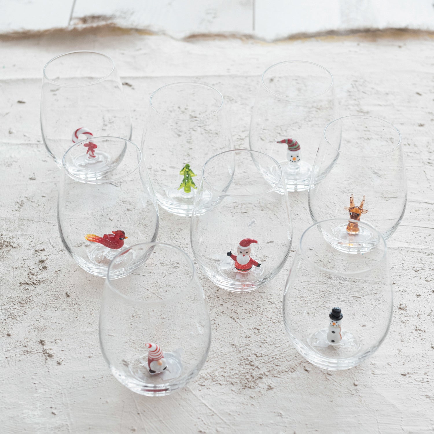 Assorted Christmas stemless wine glasses with miniature Santa snowman reindeer cardinal tree and candy cane figures