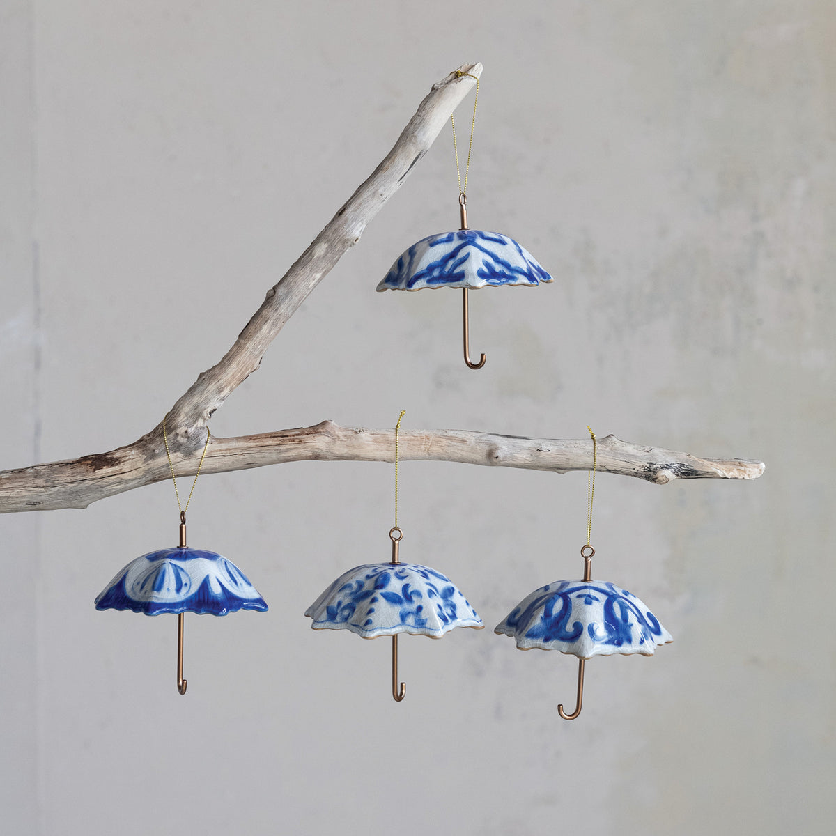 Four assorted blue and white stoneware umbrella Christmas ornaments with curved metal handles